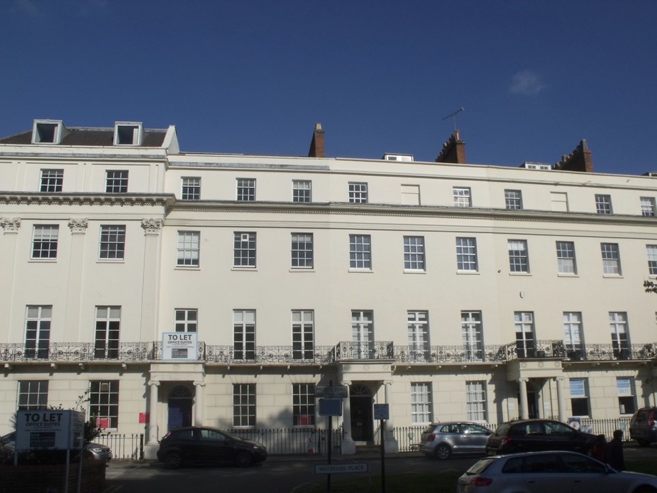 A long white stucco terrace of Regency houses on a street in England